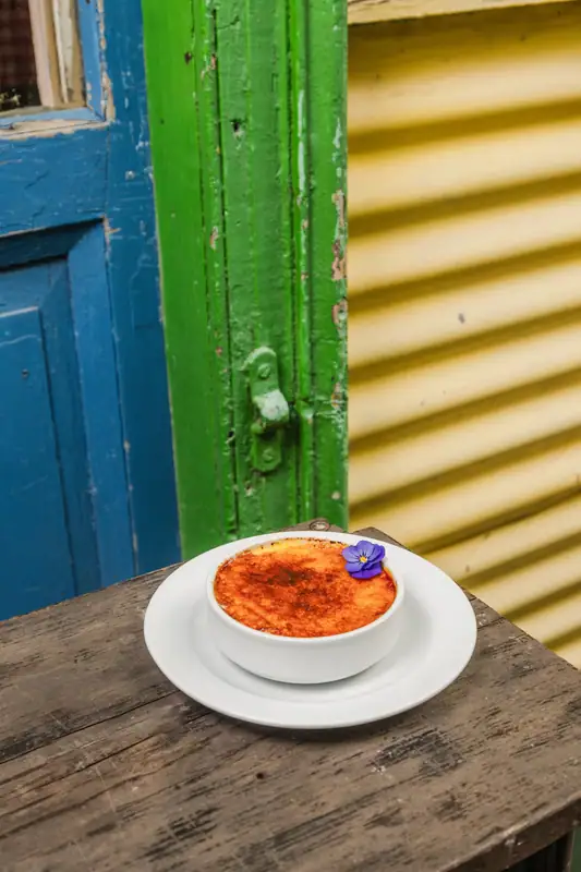 Postre servido frente a una pared de chapa de colores en El Gran Paraíso, La Boca
